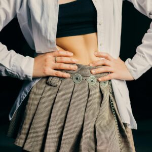 Stylish woman wearing a plaid skirt, crop top, and open shirt. Fashion trend.